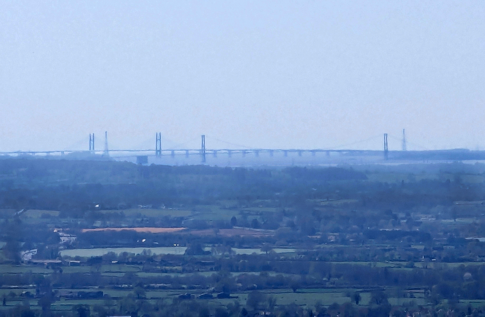 Low quality image of two bridges crossing a river, with various fields before the bridge