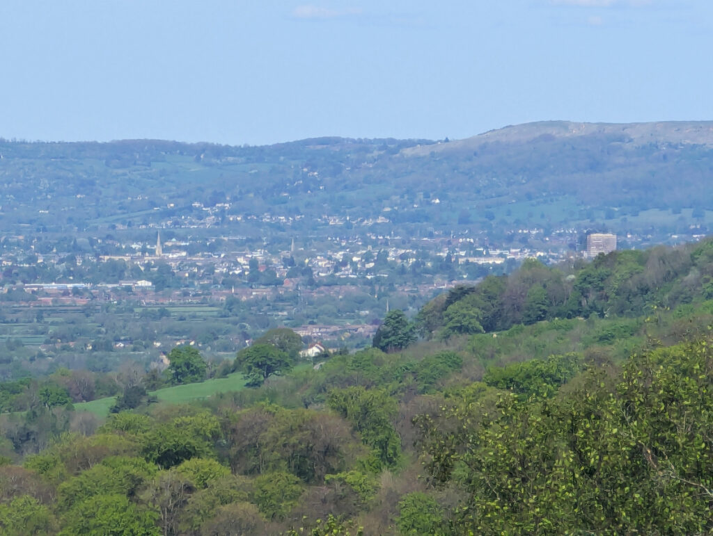 A picture of a large built up area over a hill, with another hill in the background