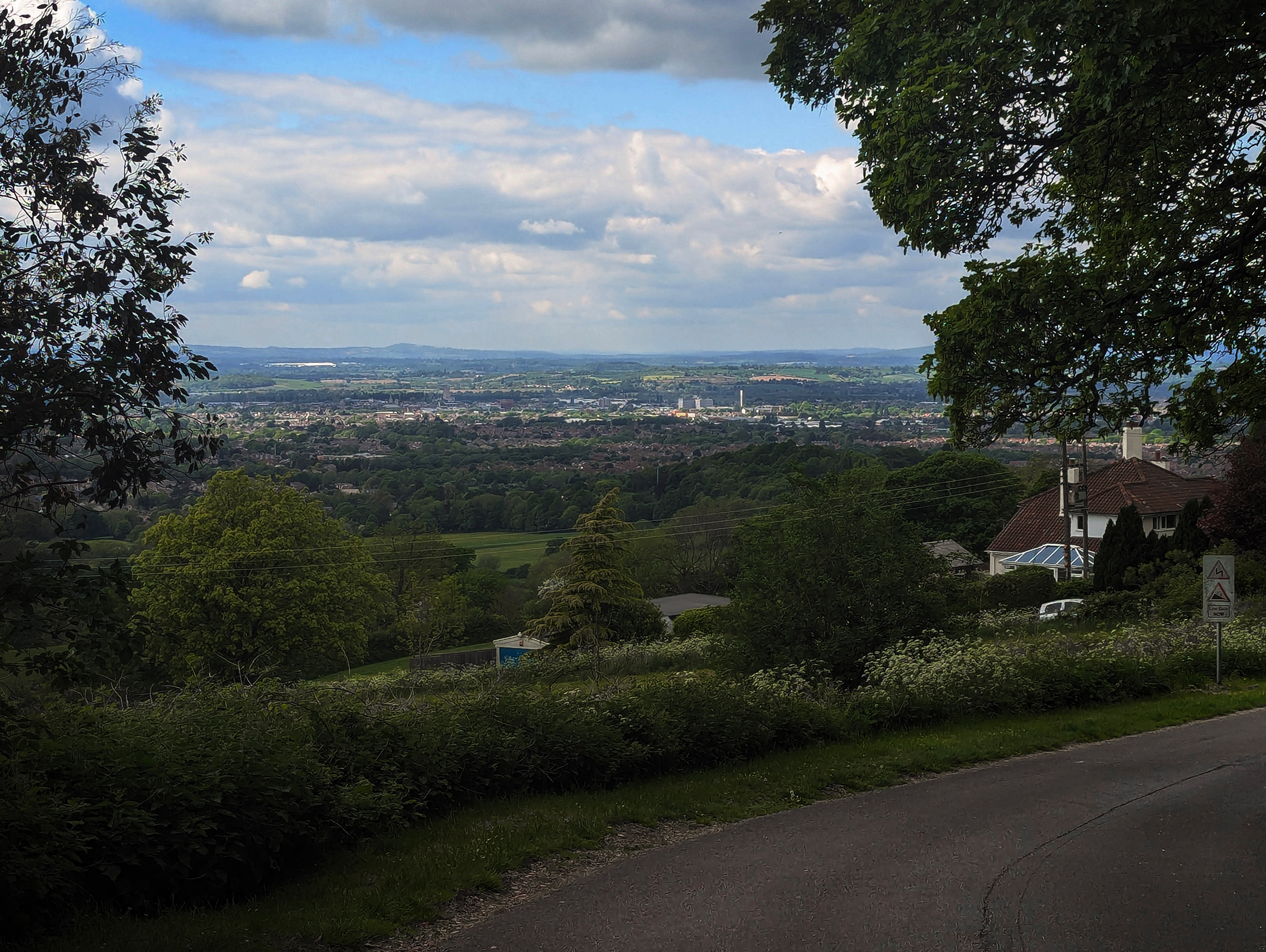 Picture of a city. The photographer is standing on a road on a hill.