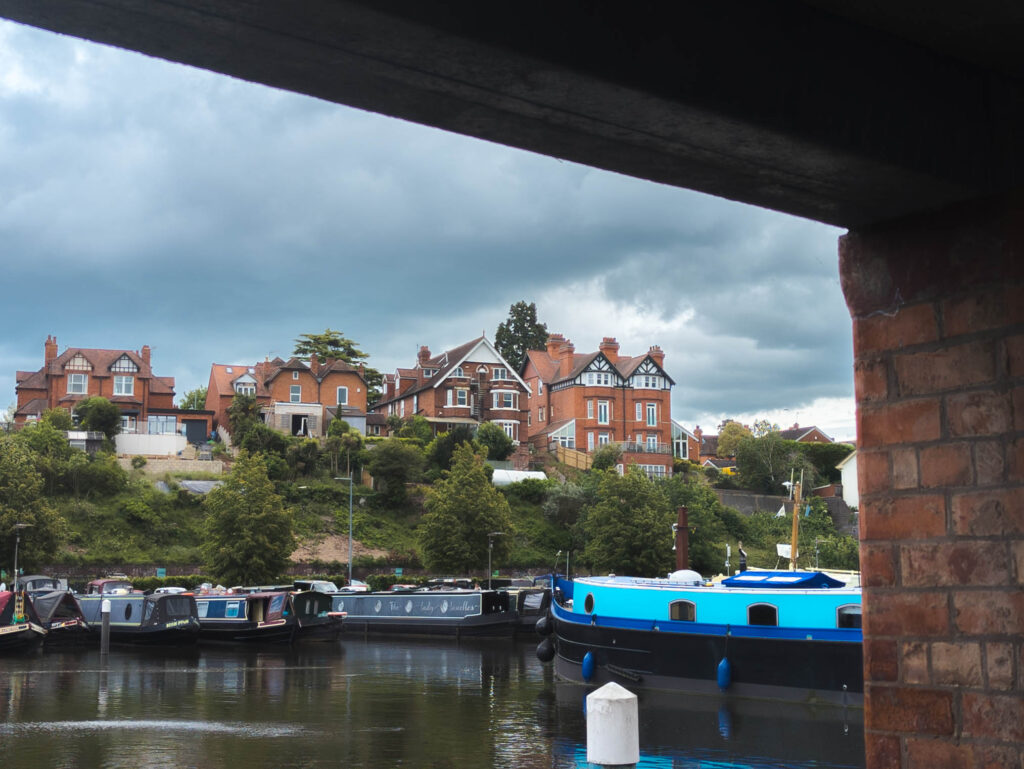 A picture of boats docked with houses above. Photo taken in shade.