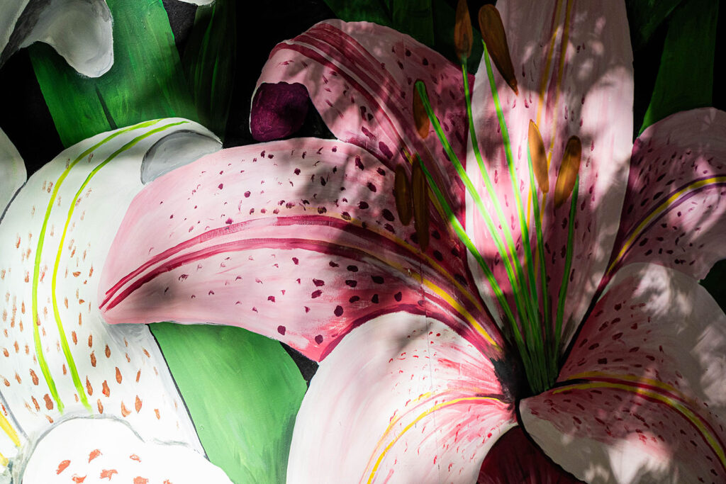 Flower artwork on a wall with a reflection of a flower visible too