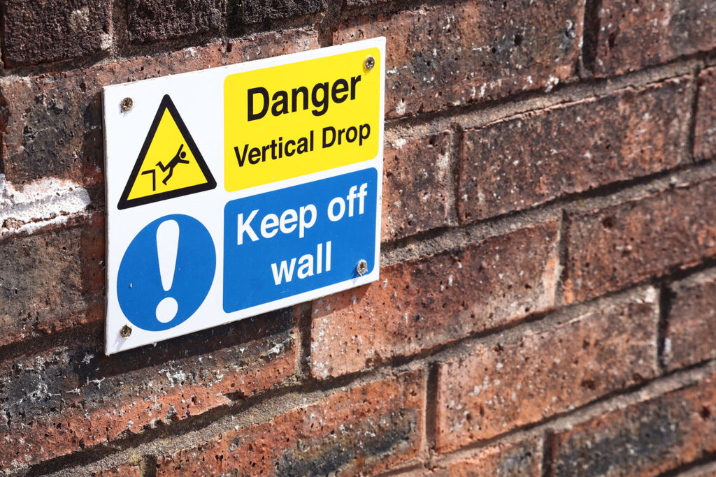 Sign on a wall warning of a vertical drop