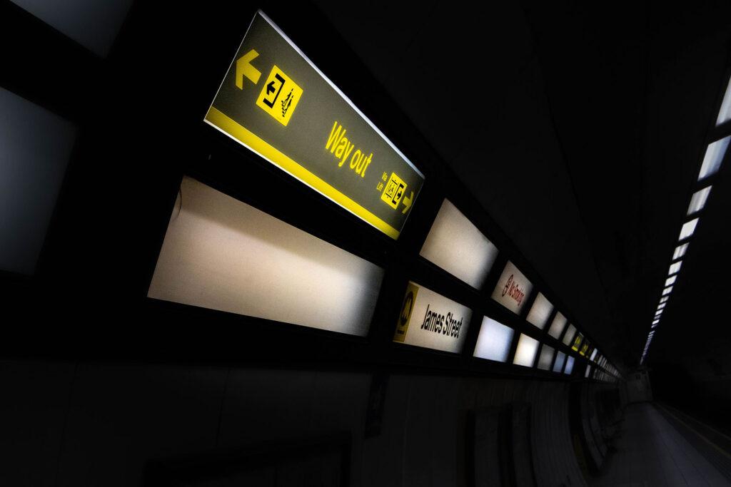 A very dark train station with only lights and signage lit up