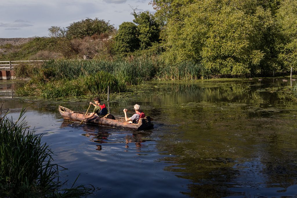 Two men using a wooden canoe navigating down